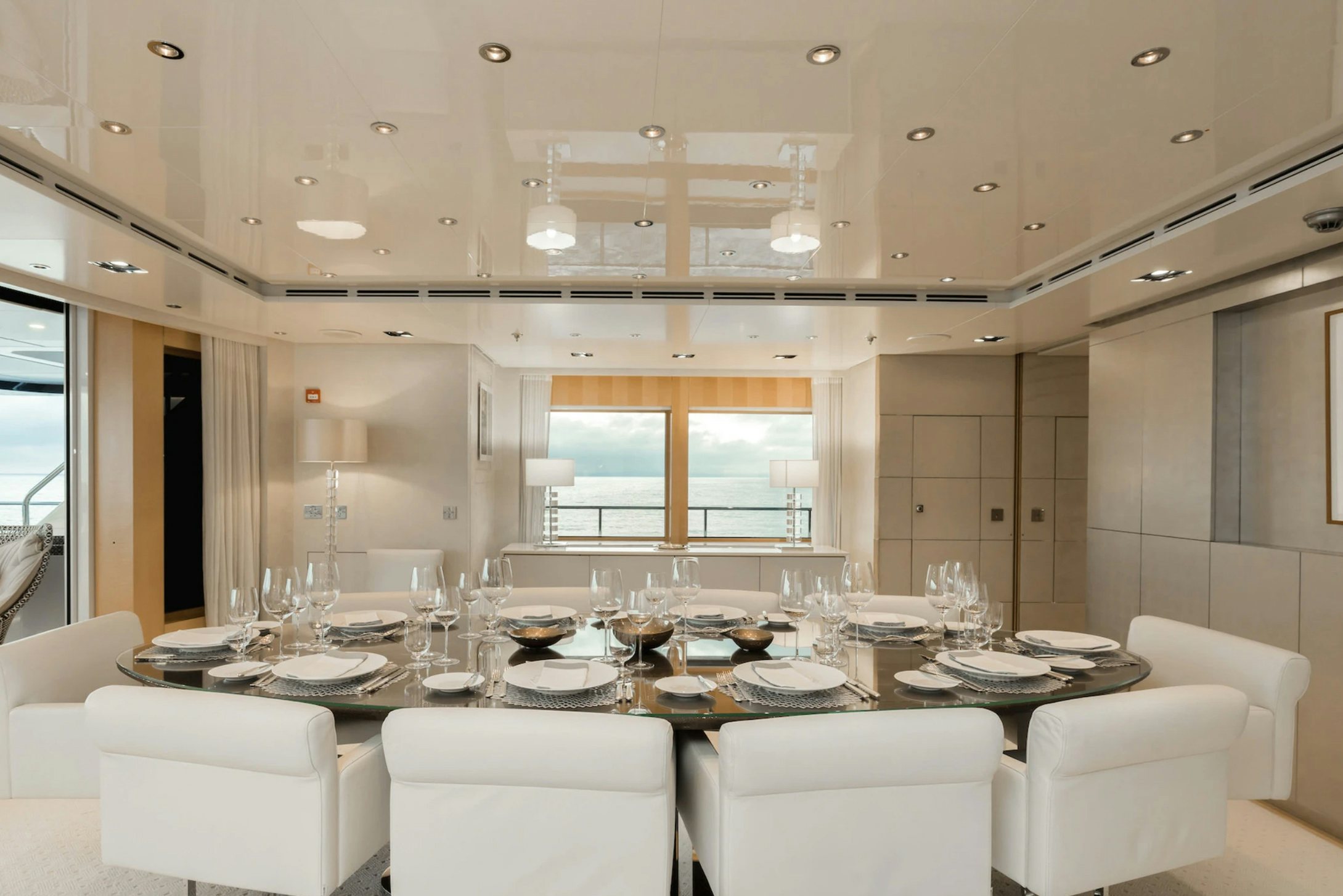 a dining room with white chairs and white tables aboard LOON Yacht for Charter