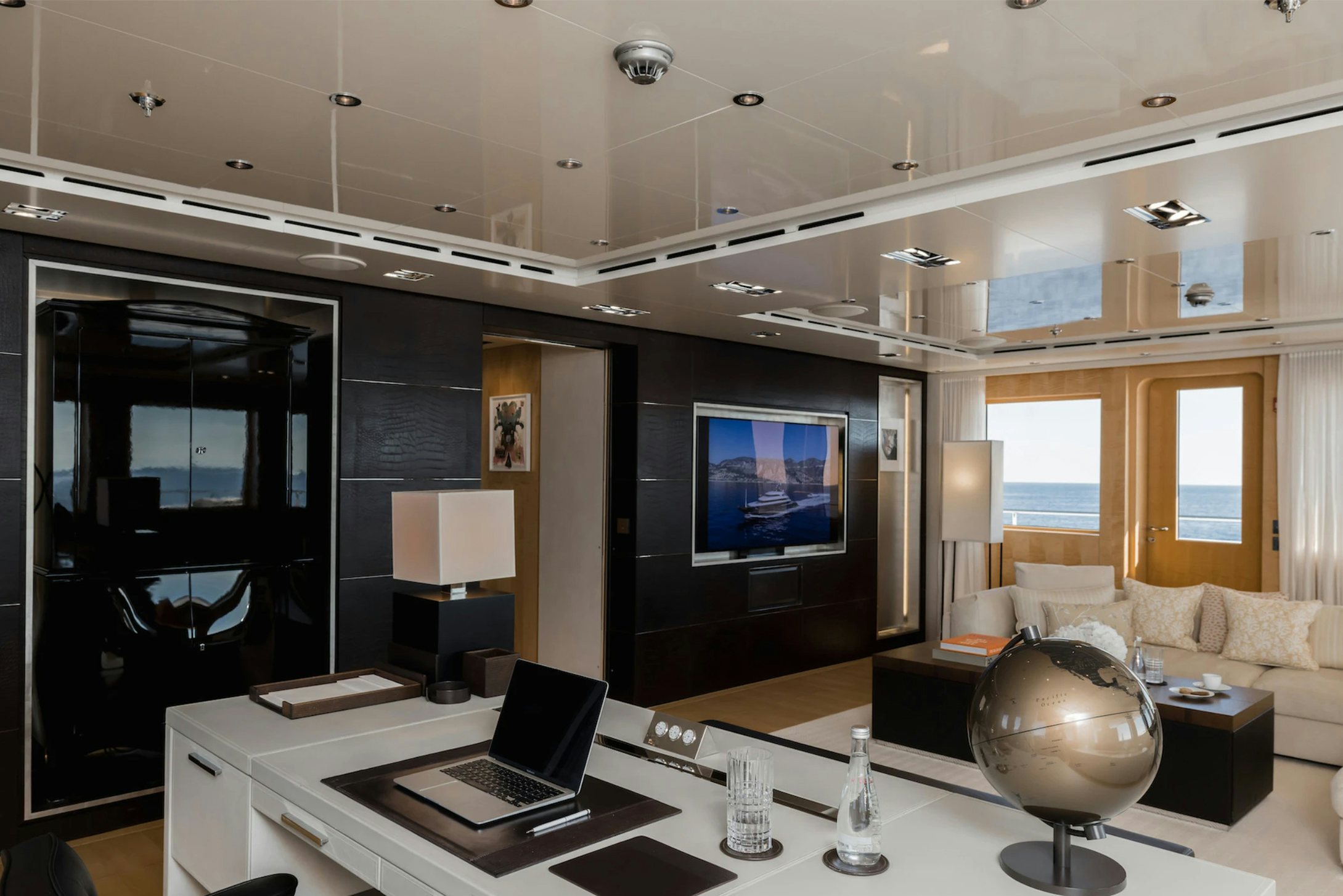 a room with a large television and a laptop on a table aboard LOON Yacht for Charter