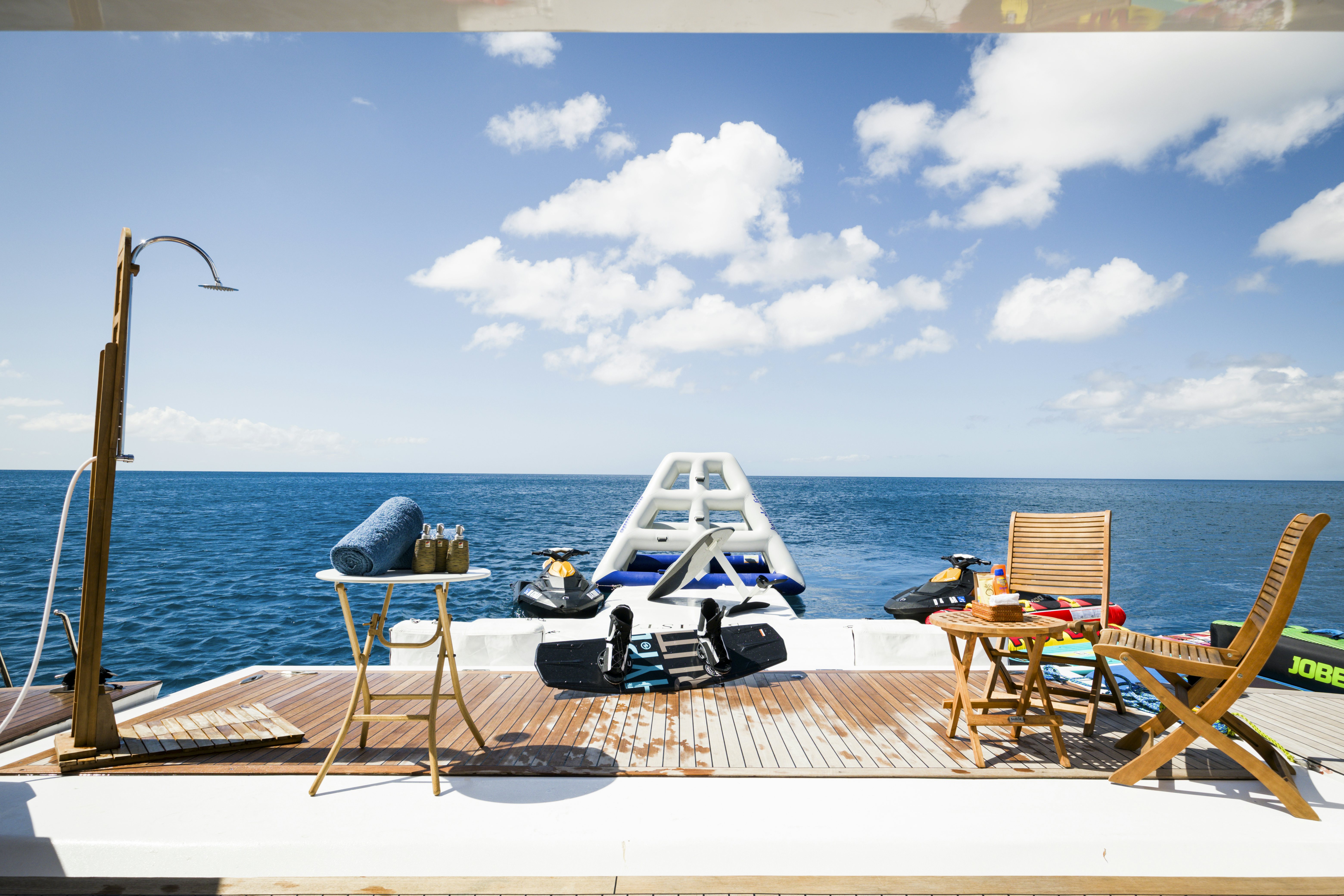 a deck with chairs and a table on it by the water aboard BALISTA Yacht for Sale