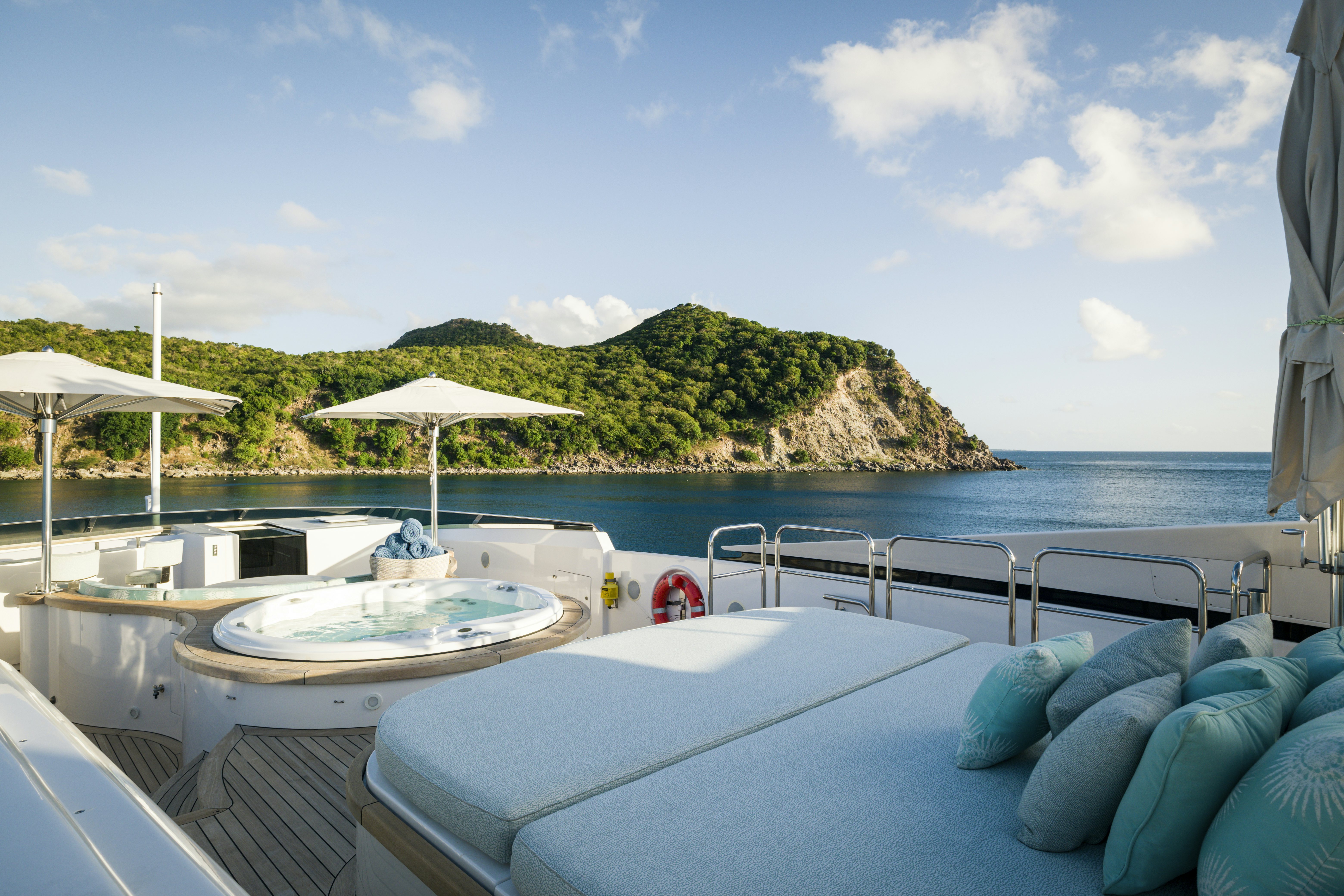 a pool with a large rock wall and a beach with a large rock formation and blue sky and aboard BALISTA Yacht for Sale