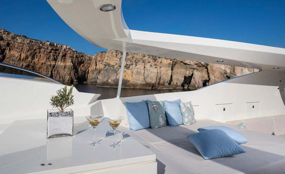 a large white room with a large white bed and a large rock wall aboard RINI V Yacht for Charter