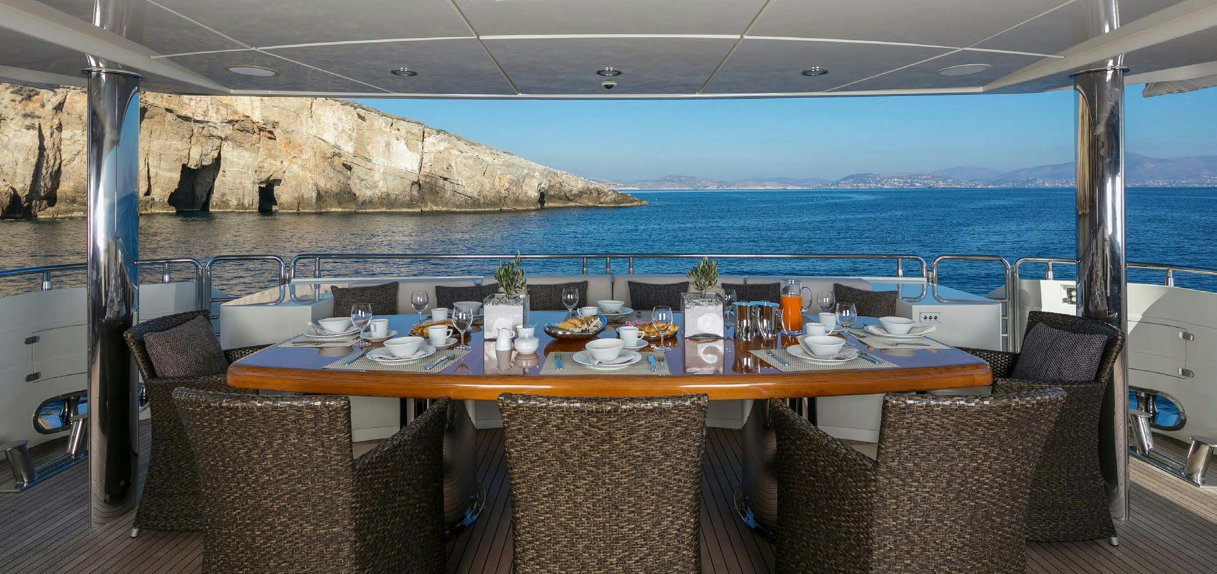 a table with chairs and a view of the ocean aboard RINI V Yacht for Charter