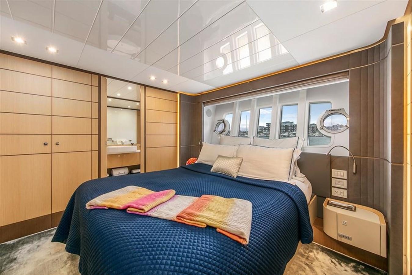 a bedroom with a bed and a window aboard LONTANO Yacht for Sale