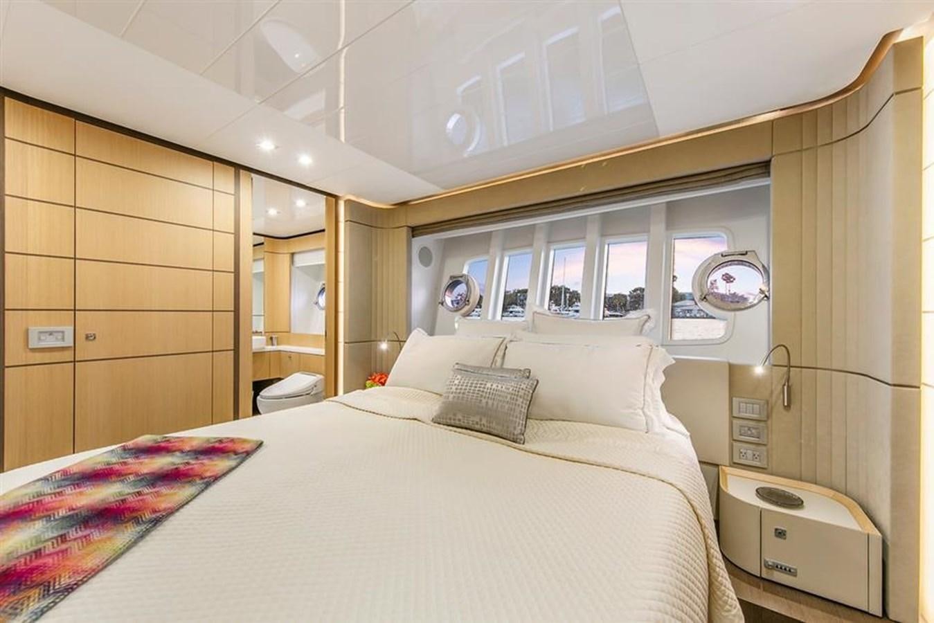 a bed with a white sheet and pillows in a room with wood walls aboard LONTANO Yacht for Sale