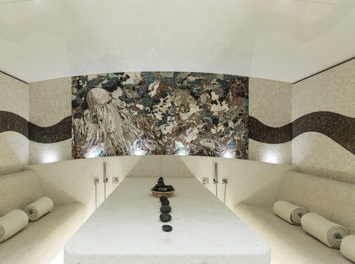 a room with a bed and a table with a lamp on it aboard DRAAK Yacht for Sale