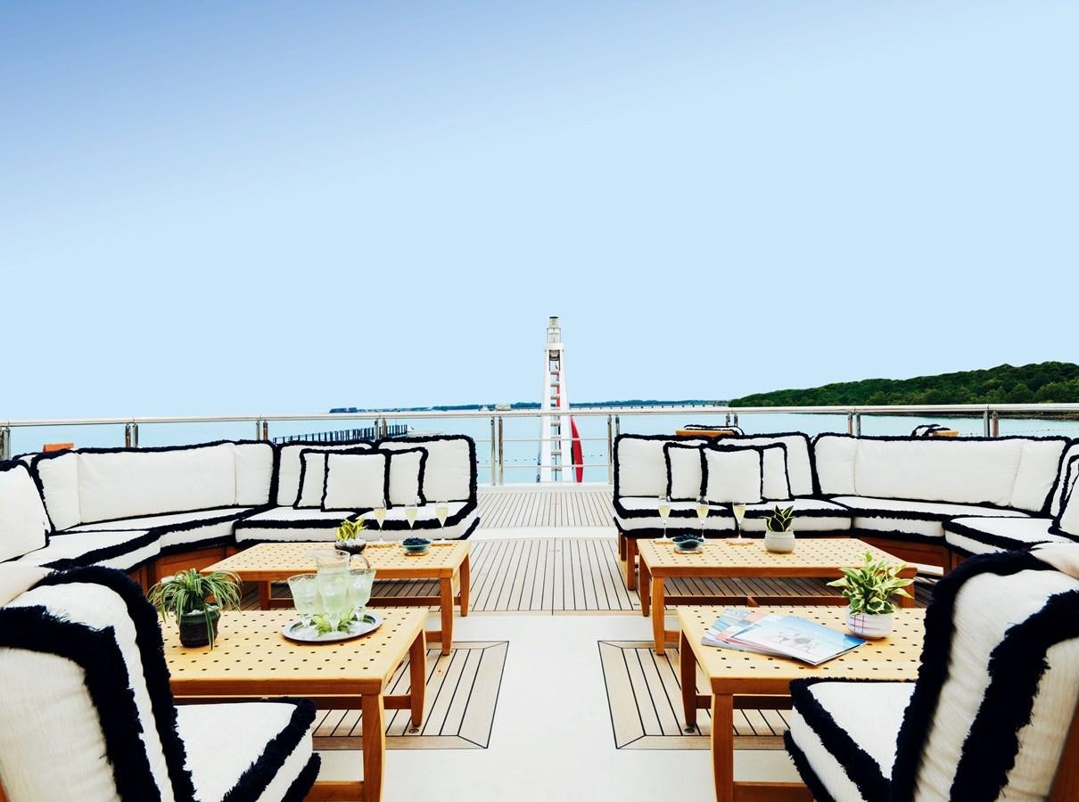 a deck with a table and chairs on it aboard DRAAK Yacht for Sale