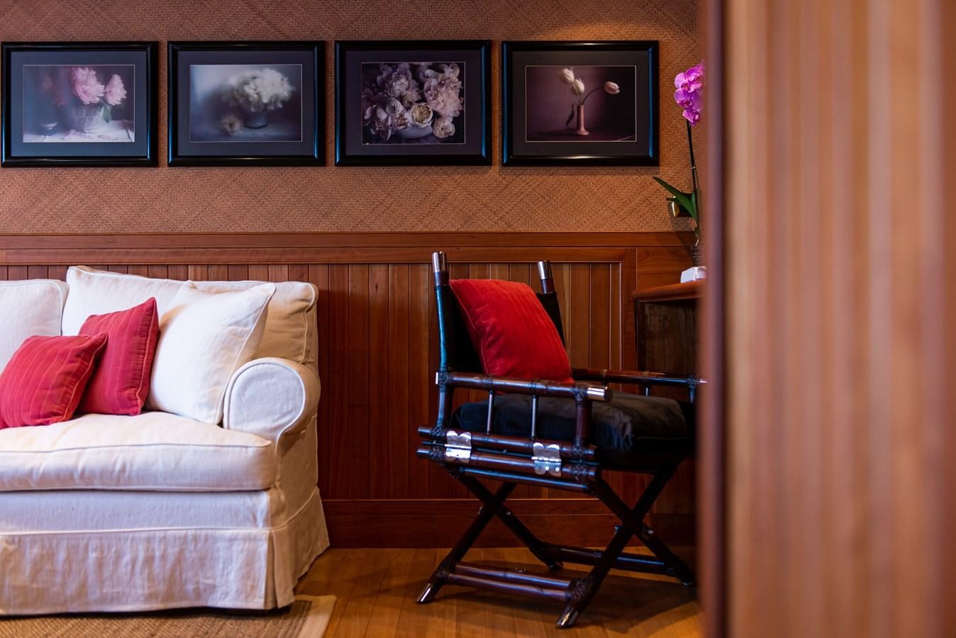 a chair and a couch in a room with a wood wall and pictures aboard BLEU DE NIMES Yacht for Sale