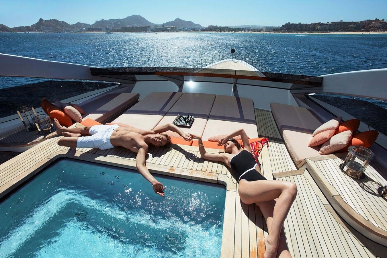 a person lying on a lounge chair on a deck of a boat aboard HALO Yacht for Sale