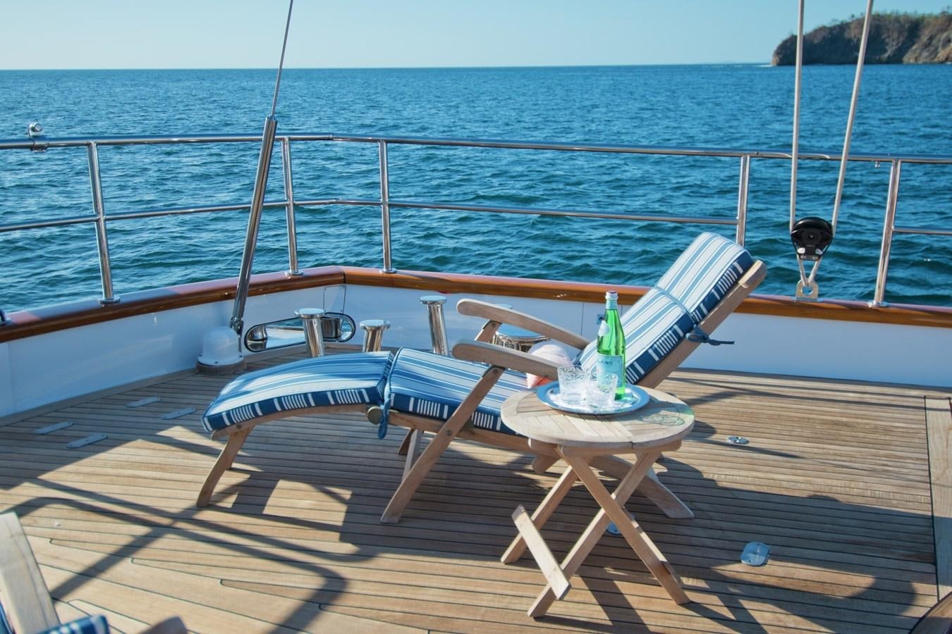 a glass bottle on a table on a beach aboard MORNING GLORY Yacht for Sale