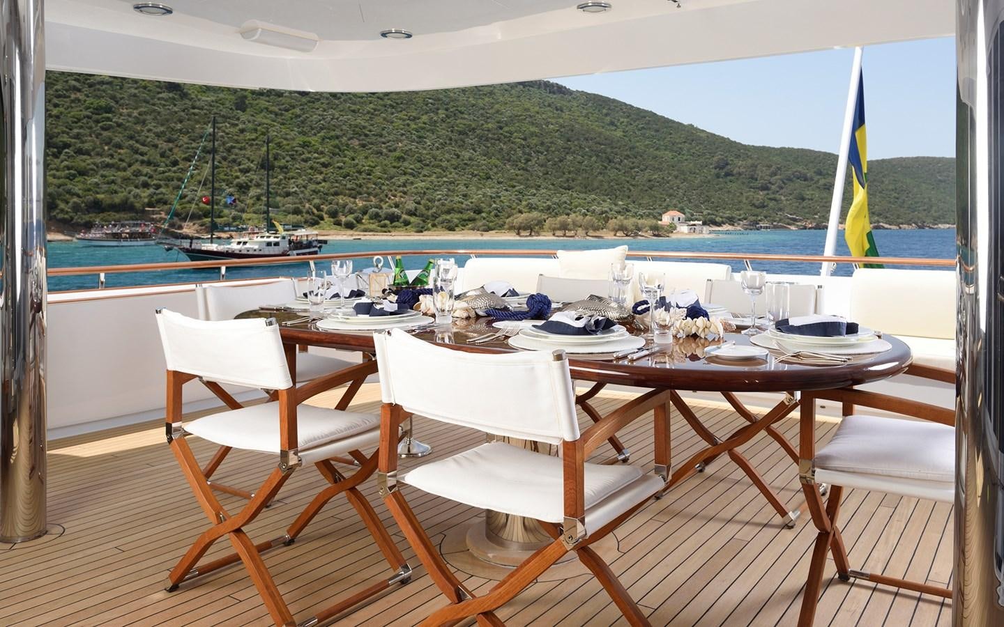 a table and chairs on a deck overlooking a body of water aboard AZZURRA II Yacht for Sale
