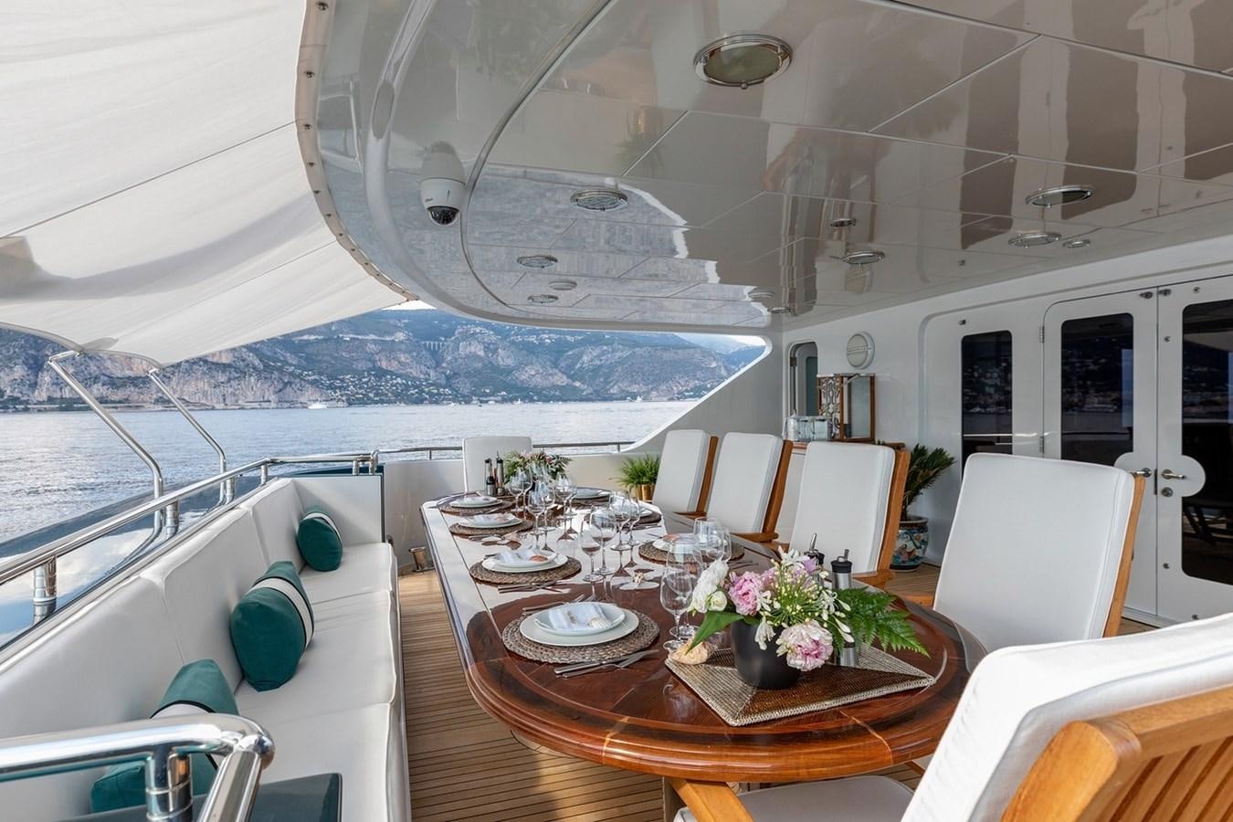 a table with chairs and a large window overlooking a beach aboard SIERRA 2 Yacht for Sale