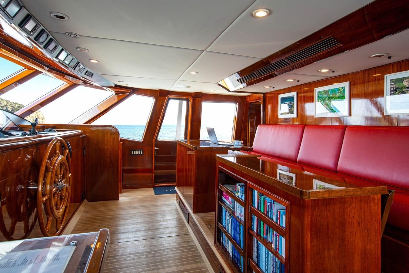 a room with a wood floor and a wood cabinet with books on it aboard MIKADO Yacht for Sale