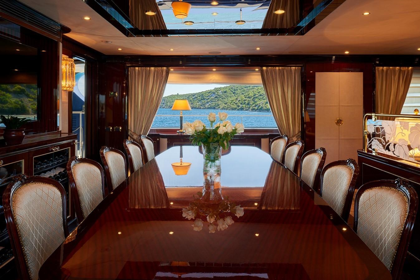 a dining room table with chairs and a large window aboard REVE D’OR Yacht for Sale