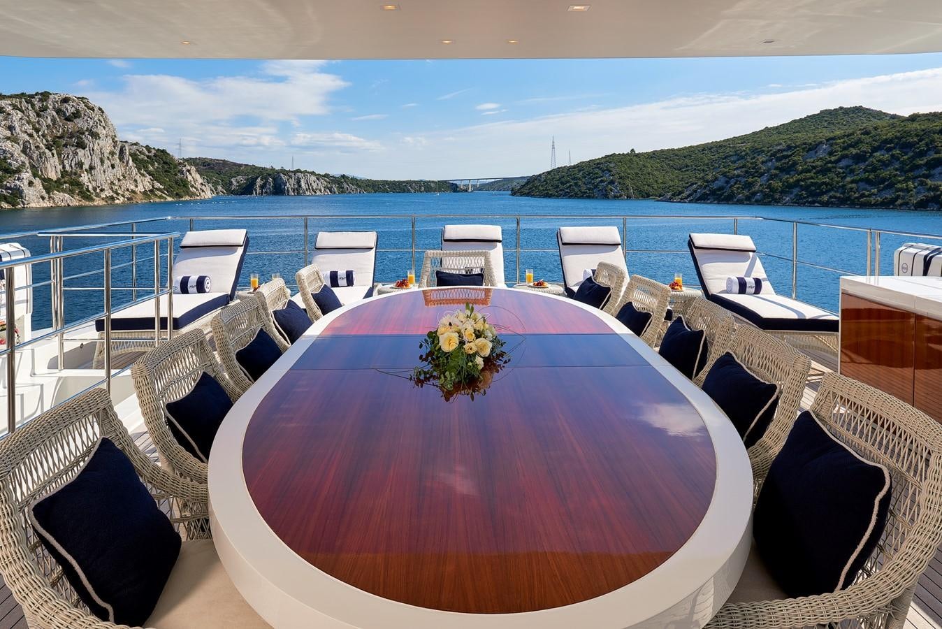 a table with chairs on it next to a body of water aboard REVE D’OR Yacht for Sale