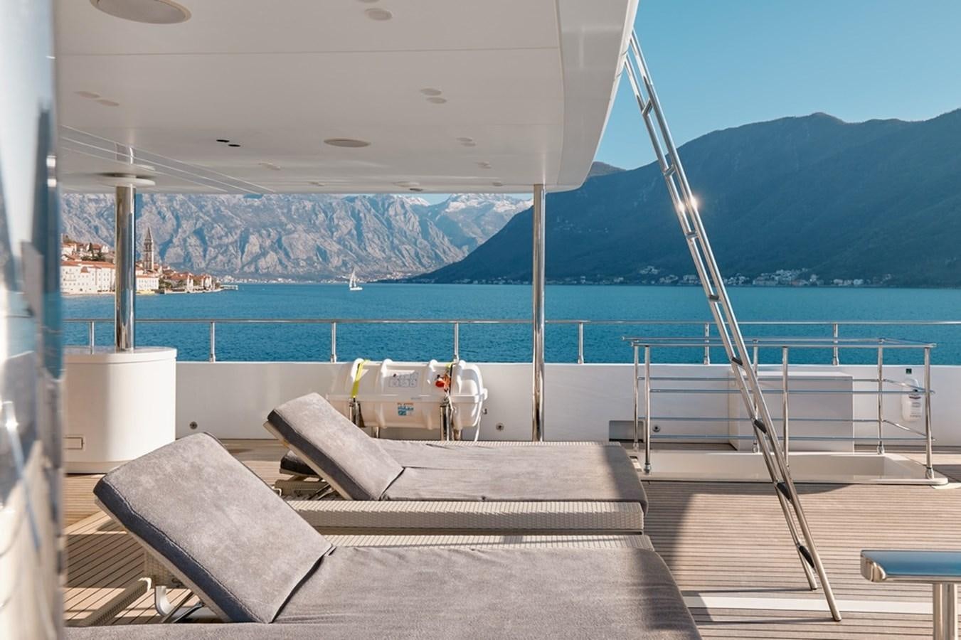 a deck with a view of a body of water and mountains in the background aboard DEEP STORY Yacht for Sale