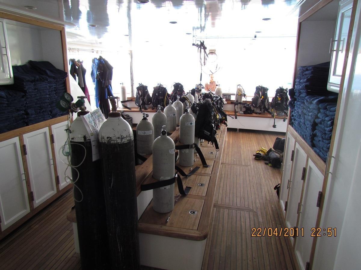 a room with many bottles on the floor and people standing in the background aboard SCUBA SCENE Yacht for Sale