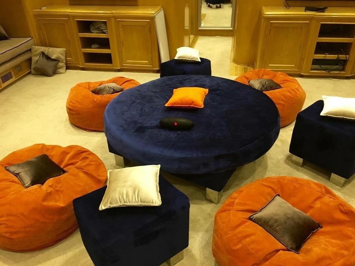 a room with a bed and a blue table with orange pillows aboard SCUBA SCENE Yacht for Sale