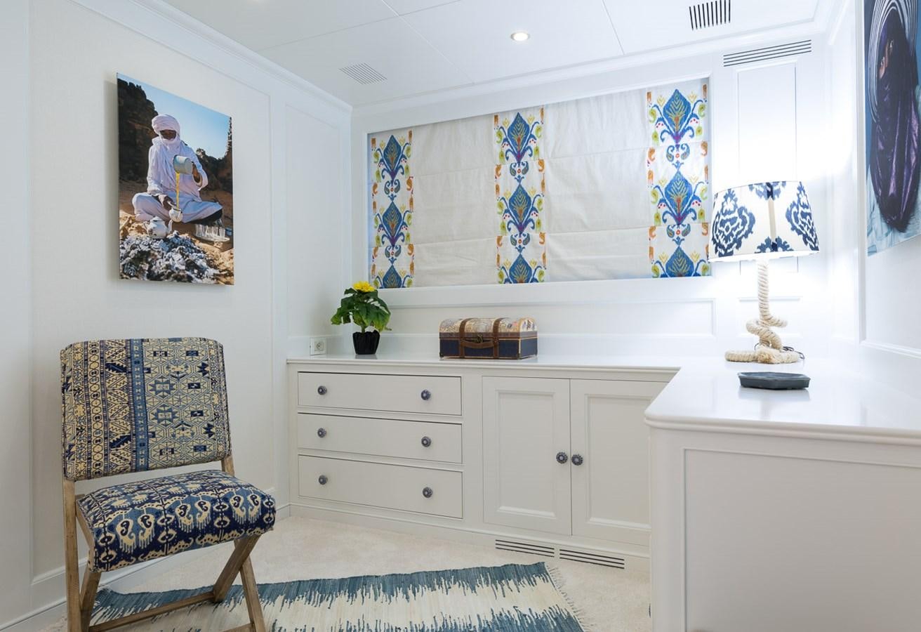 a room with a chair and a dresser and a painting on the wall aboard BINA Yacht for Sale
