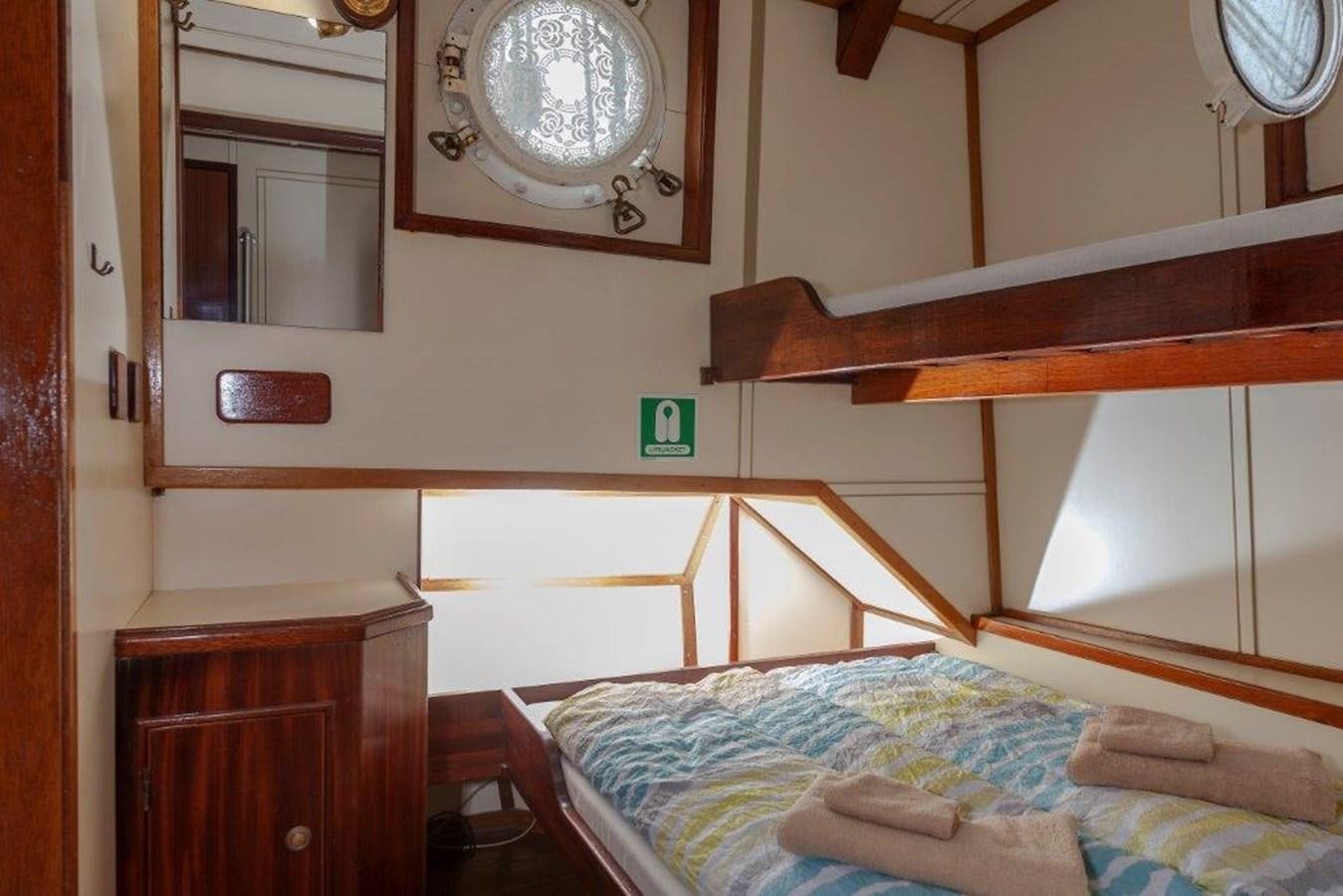 a room with a bed and a clock on the wall aboard SIR ROBERT BADEN POWELL Yacht for Sale