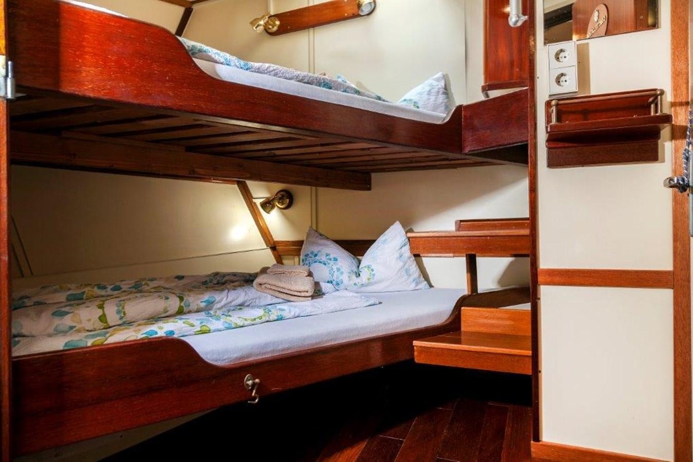 a bed with a wooden headboard aboard SIR ROBERT BADEN POWELL Yacht for Sale