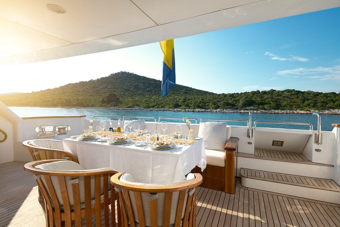 a table set for a meal on a deck overlooking a body of water aboard LADYSHIP Yacht for Charter