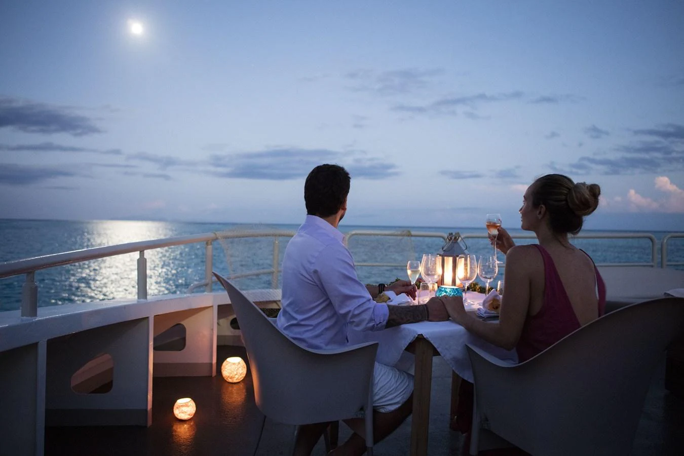a couple sitting on a boat with a view of the sunset aboard HAUMANA Yacht for Sale