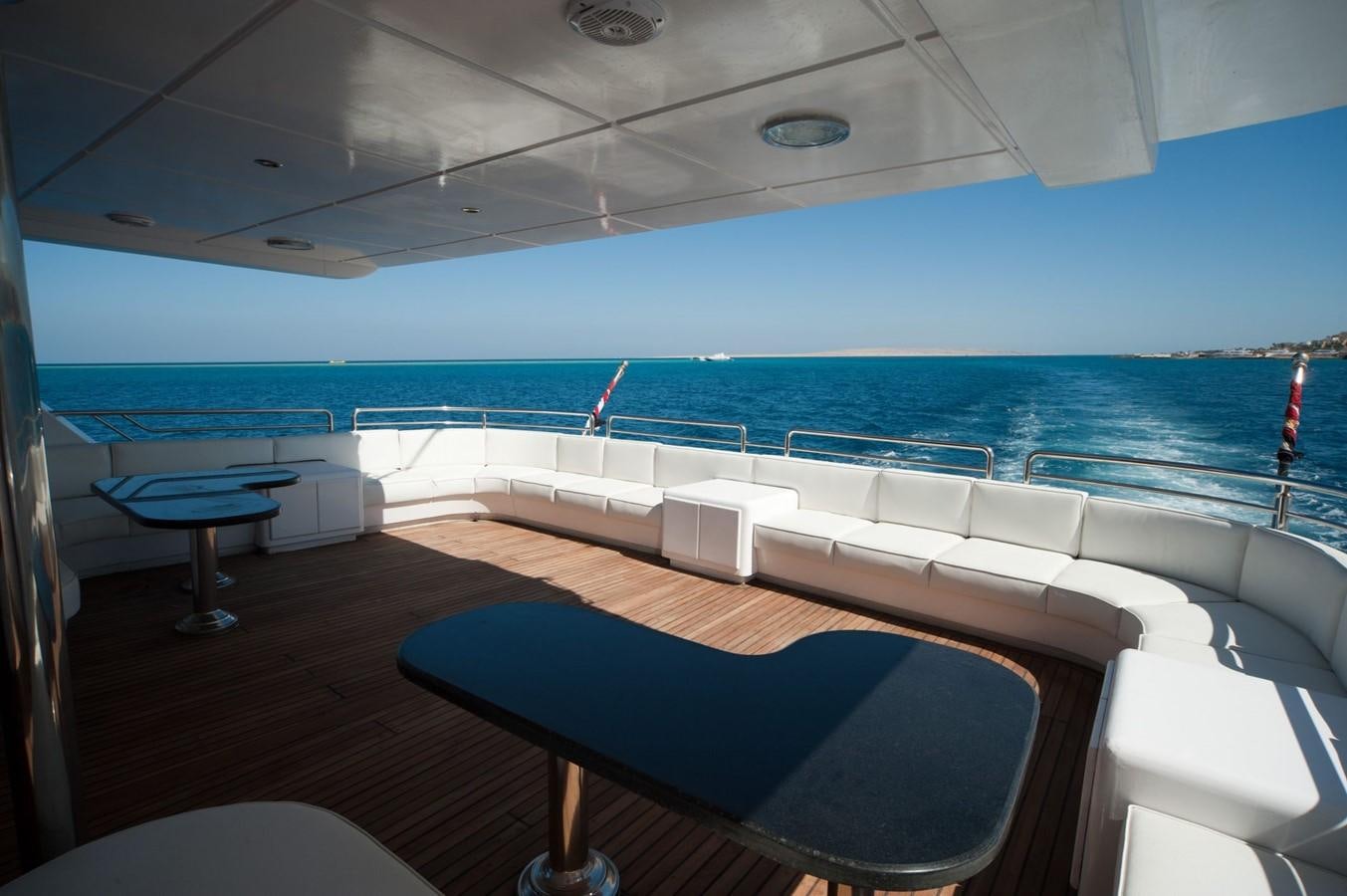 a lounge area with chairs and a pool in the background aboard BETELGUESER Yacht for Sale