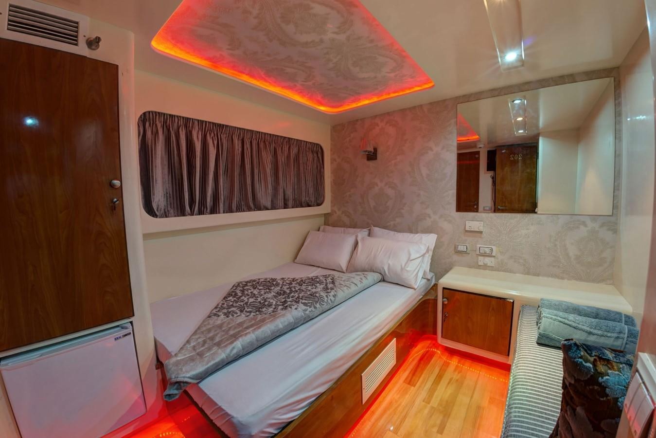 a room with a bed and a mirror aboard BETELGUESER Yacht for Sale