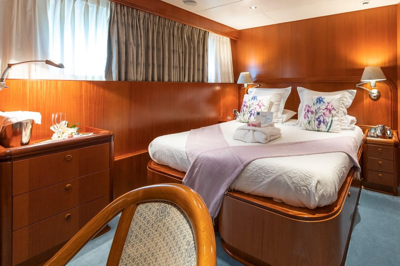 a bedroom with a bed and a chair aboard ALCOR Yacht for Charter