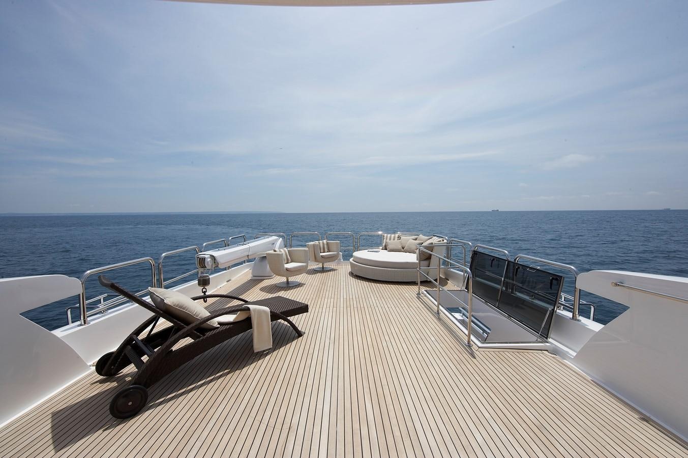 a deck with chairs and tables on it by the water aboard JOHNSON 110 FLYBRIDGE Yacht for Charter