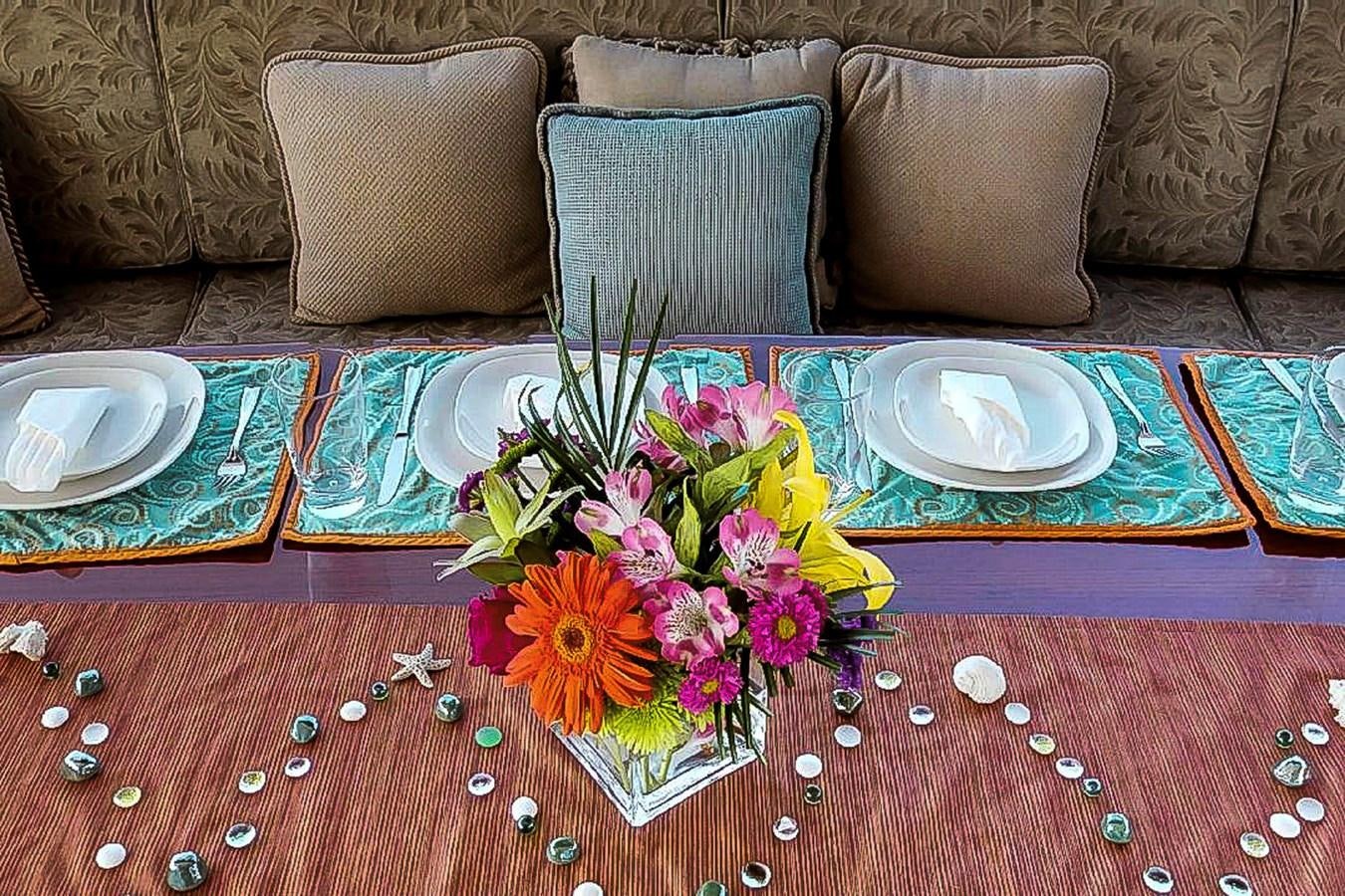 a table with plates and flowers aboard IDLETYME II Yacht for Sale