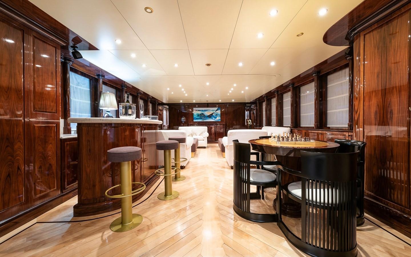 a room with a bar and stools and a table aboard BLUE MAGIC Yacht for Sale