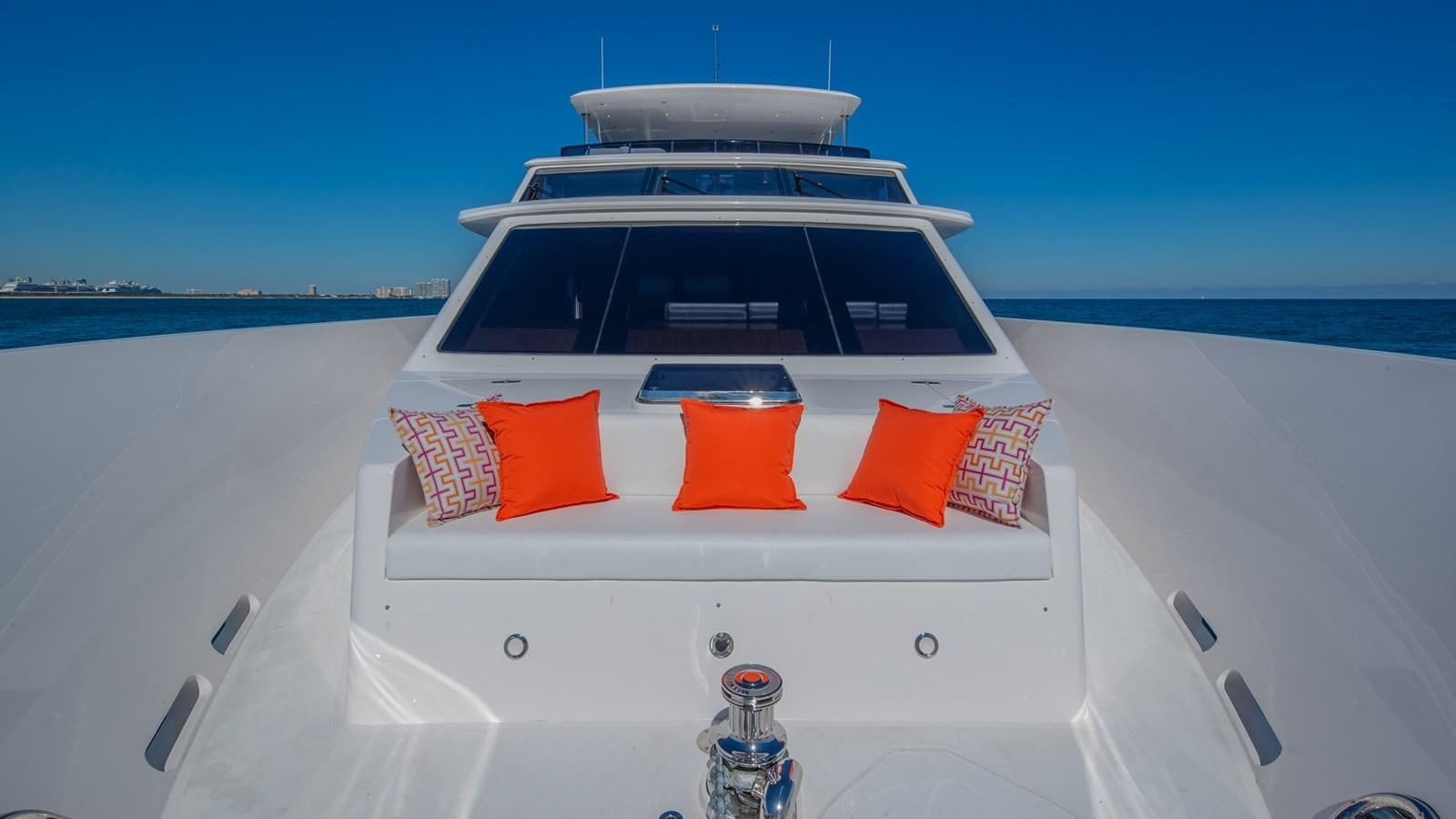 a white boat with orange and red pillows on a white surface aboard RISK TAKER Yacht for Charter