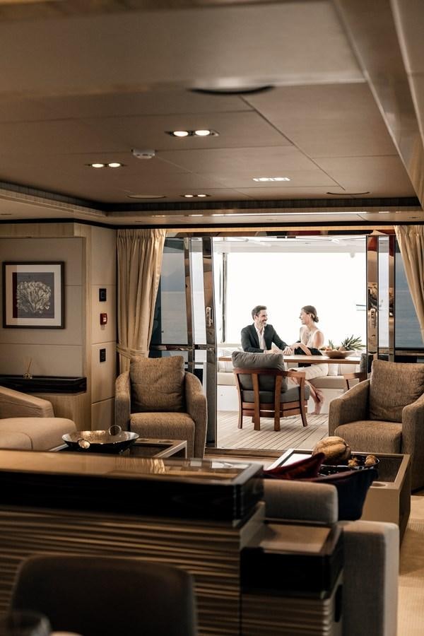 a group of people sitting at a table in a living room aboard LEGACY Yacht for Sale