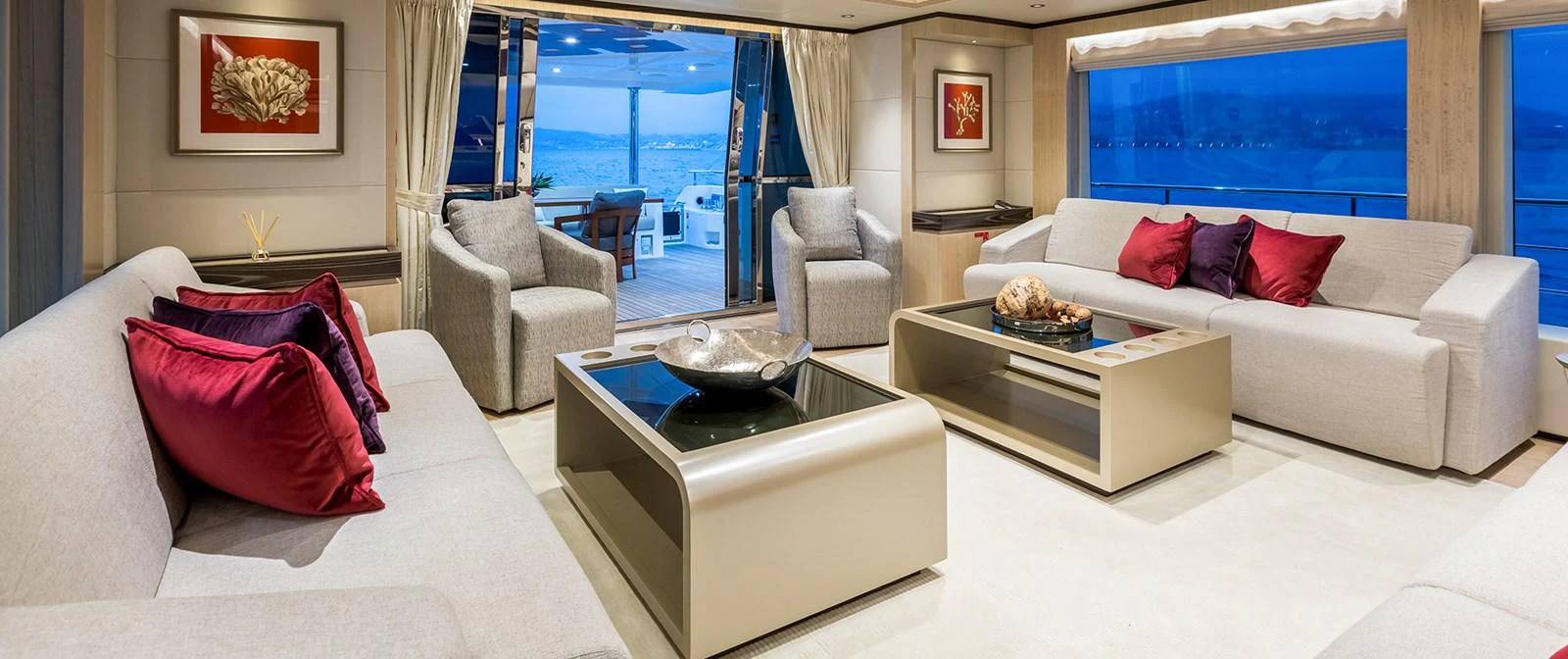 a living room with a white couch and a table with red pillows aboard BARBARA Yacht for Sale