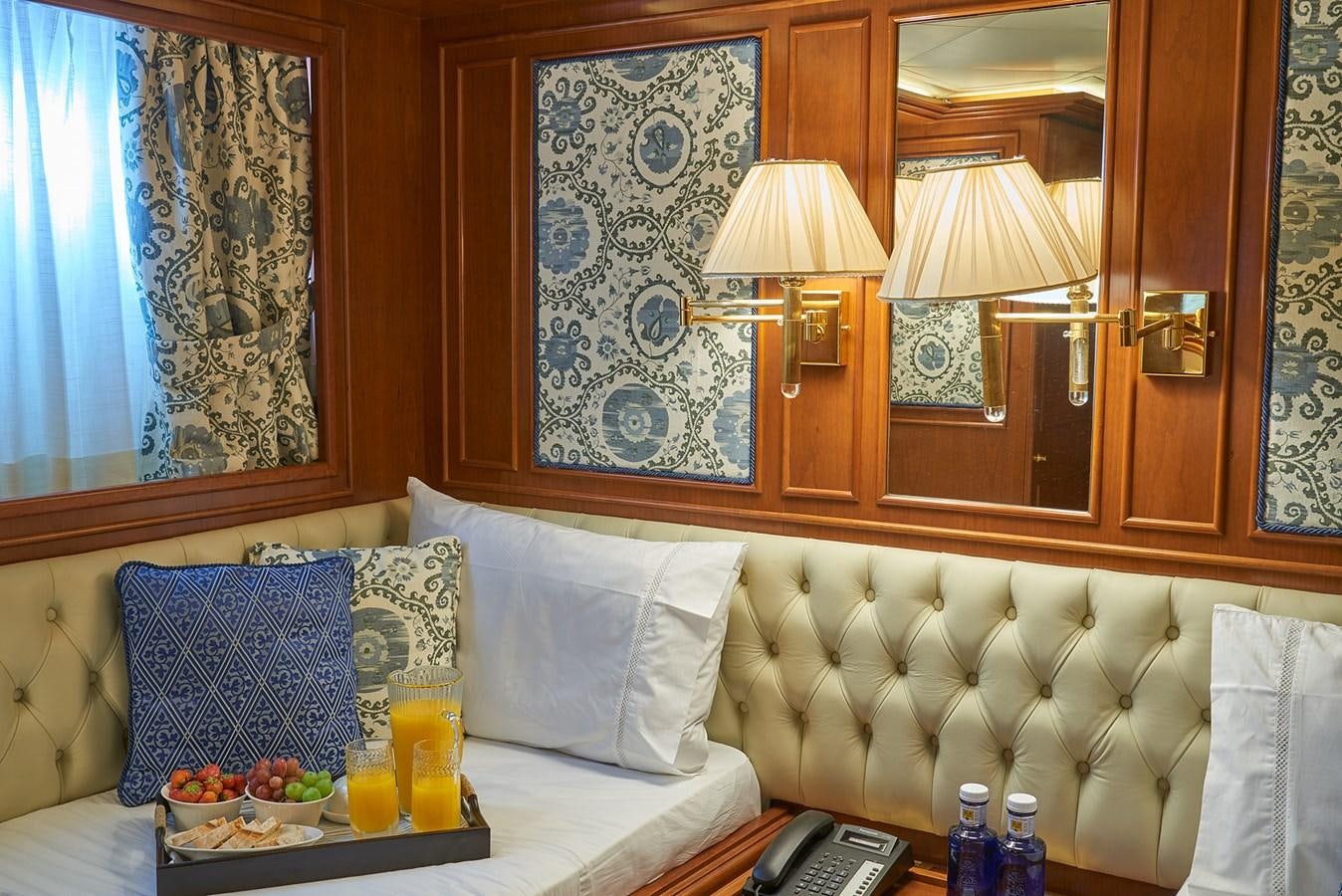 a room with a bed and a table with a phone aboard IMAGINE Yacht for Charter