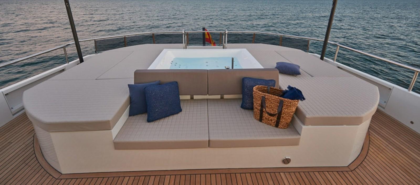 a white rectangular pool with blue cushions on a wooden deck next to a basket and a basket on aboard AST100CENROY Yacht for Sale