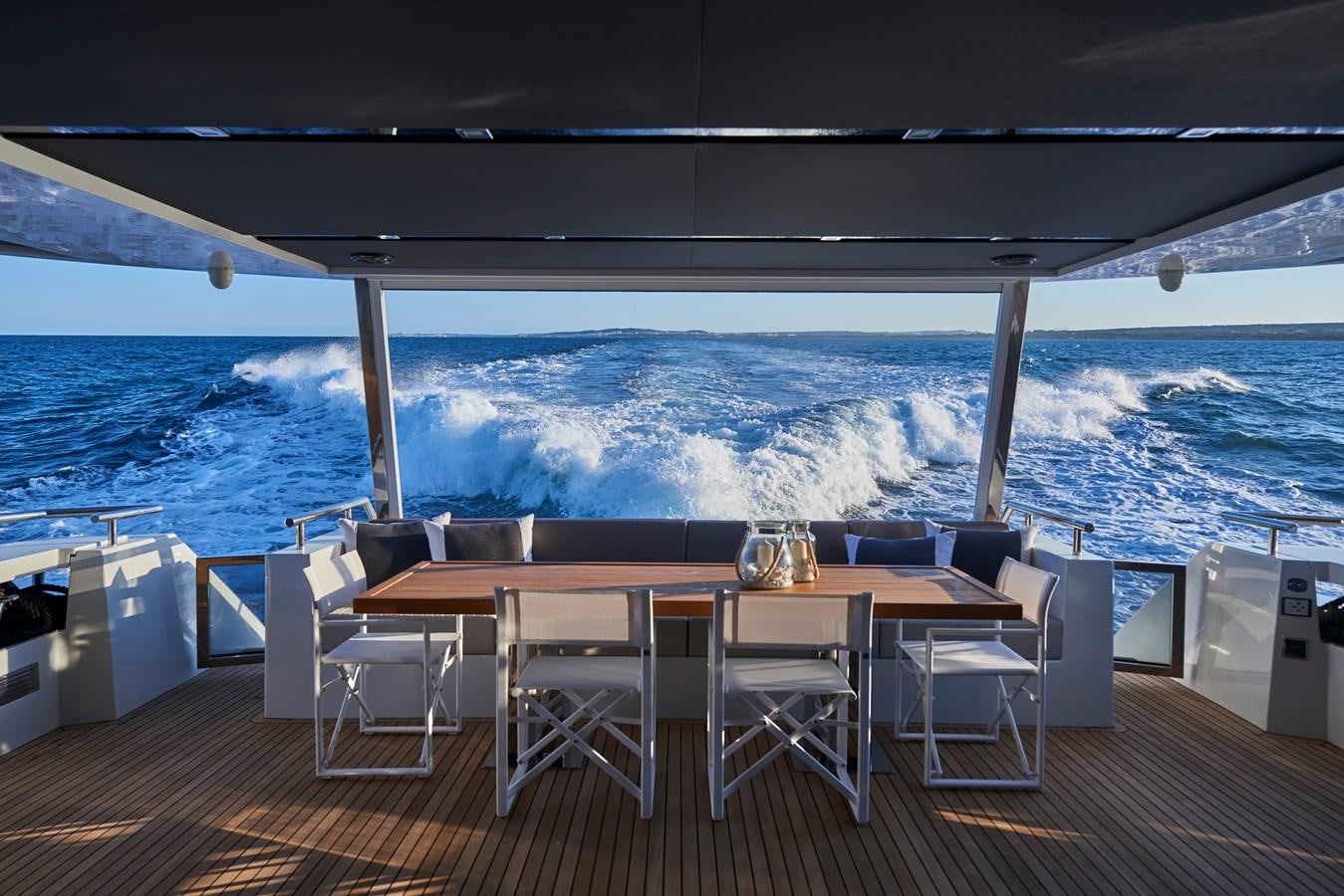 a table and chairs on a deck overlooking the ocean aboard AST100CENROY Yacht for Sale