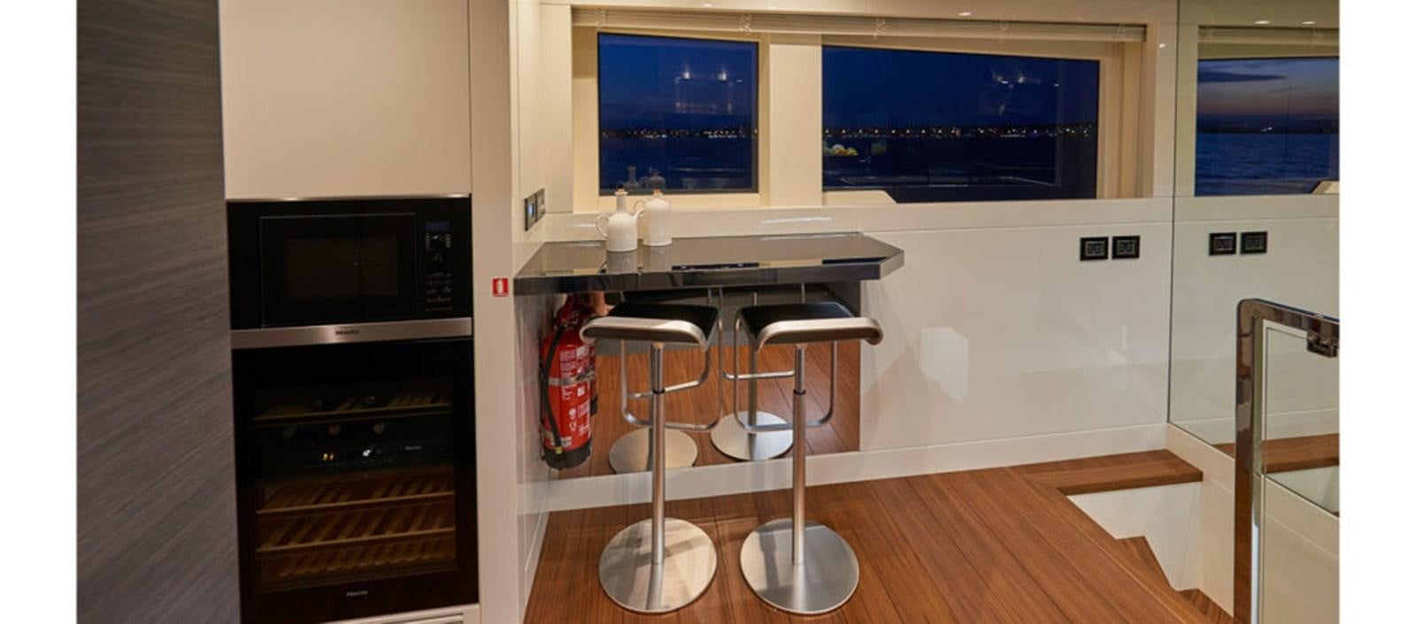 a kitchen with stools and a microwave oven aboard AST100CENROY Yacht for Sale