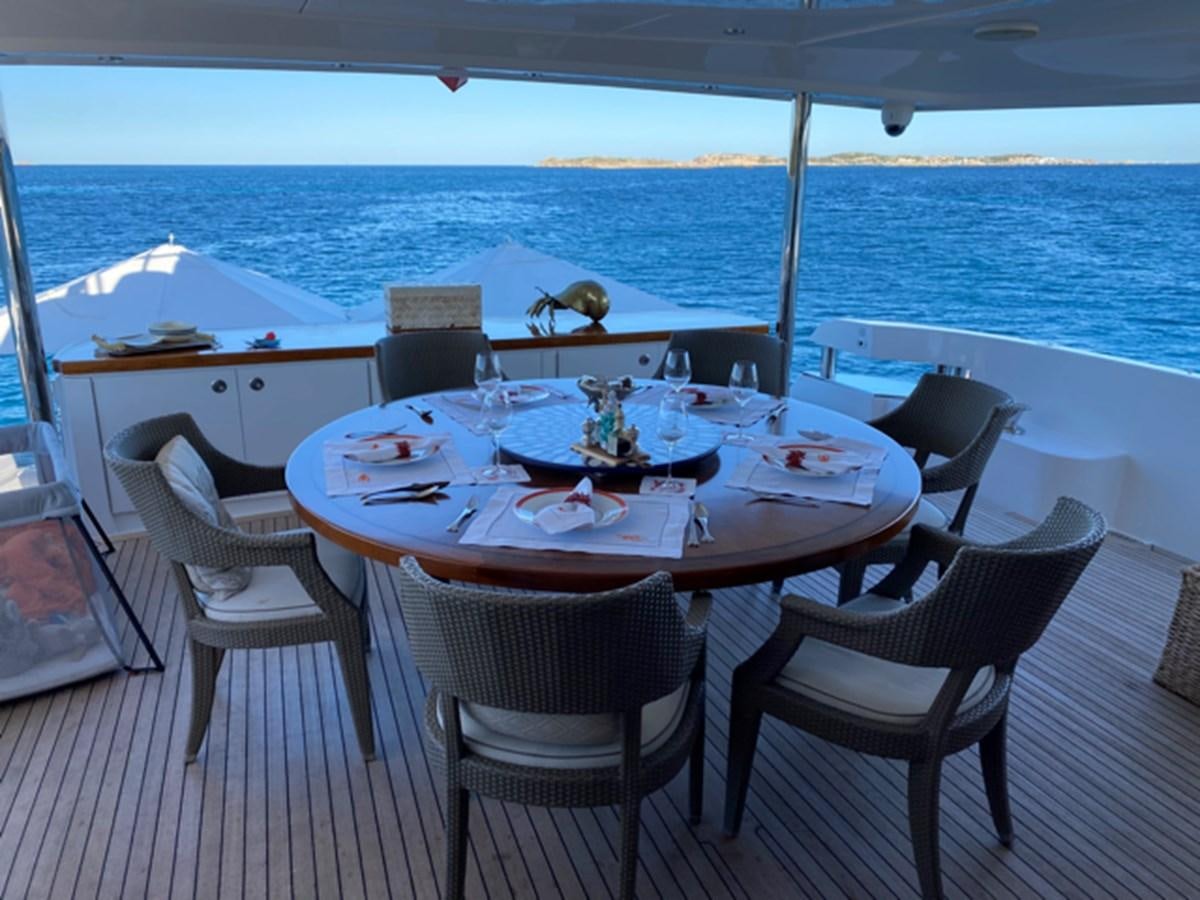 a table set for a meal on a deck overlooking the ocean aboard MAGALITA V Yacht for Sale