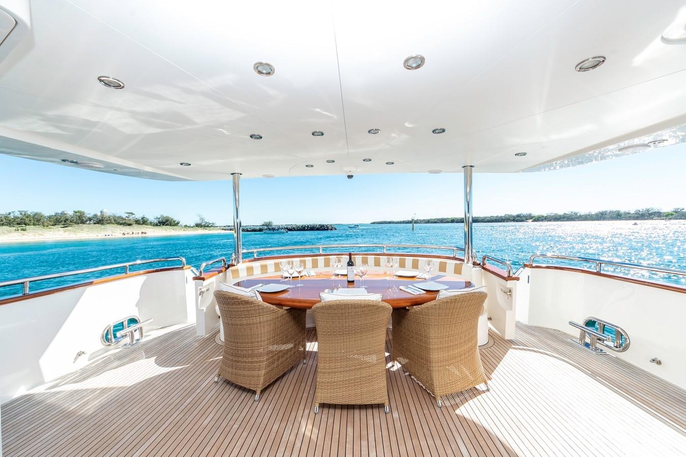 a room with a table and chairs on a deck with a view of the water and a blue aboard SUMMER WIND Yacht for Sale