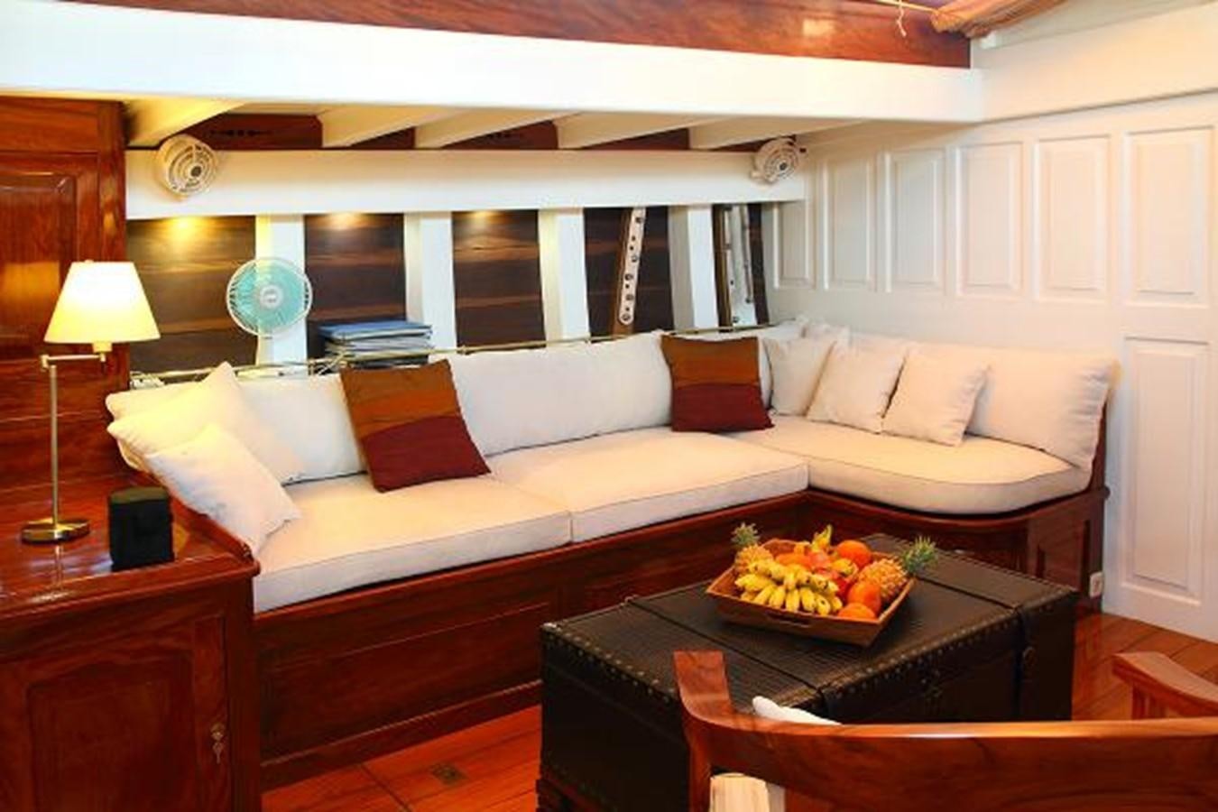 a living room with a large white couch and a large window aboard 95FT 2011 CUSTOM KETCH CLASSIC YACHT Yacht for Sale
