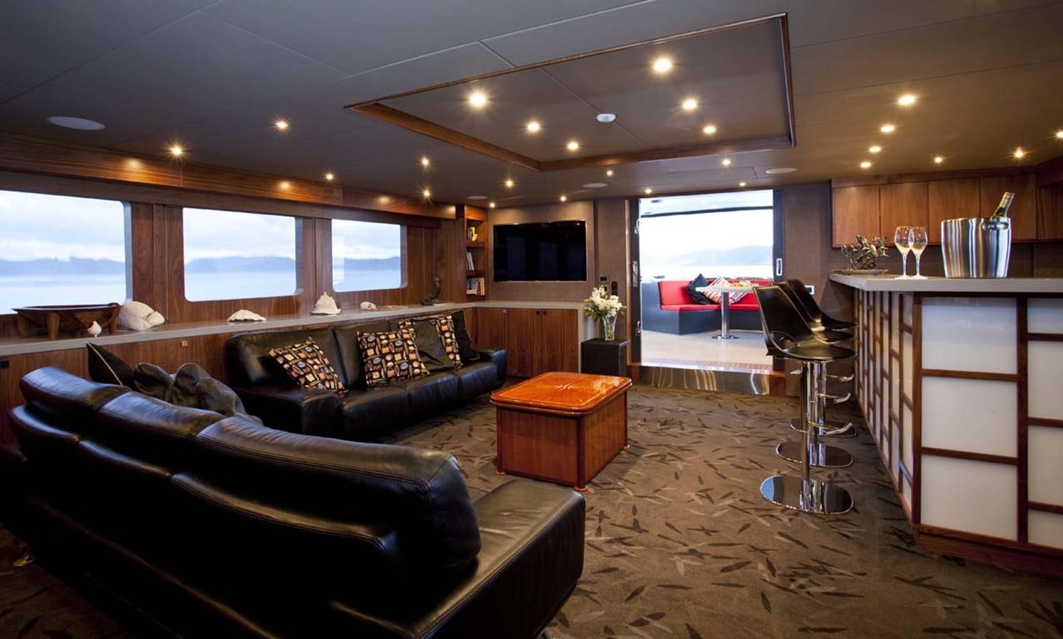 a living room with leather couches and a large window aboard PACIFIC HQ Yacht for Sale