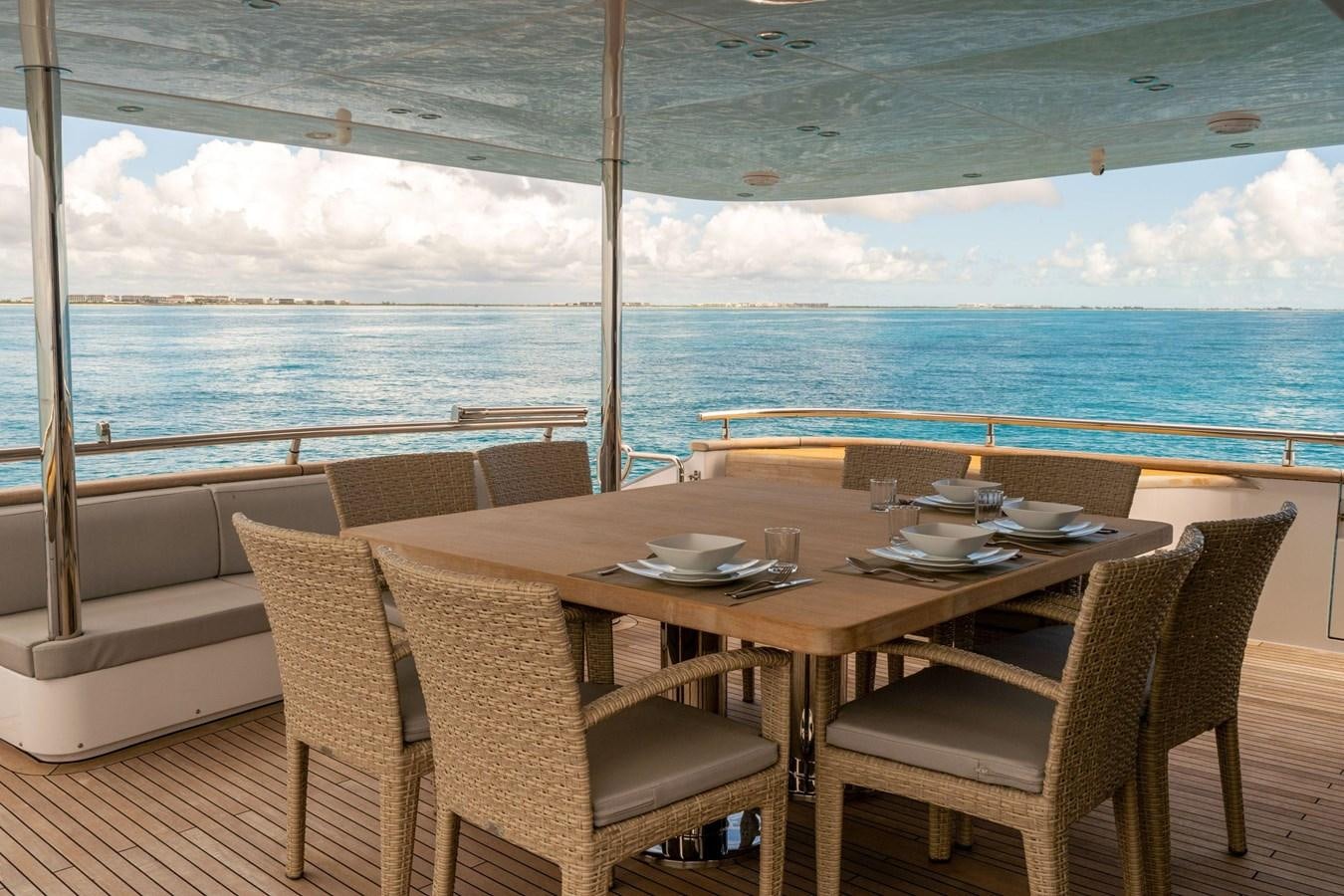 a table and chairs on a deck overlooking the ocean aboard VITA XL Yacht for Sale