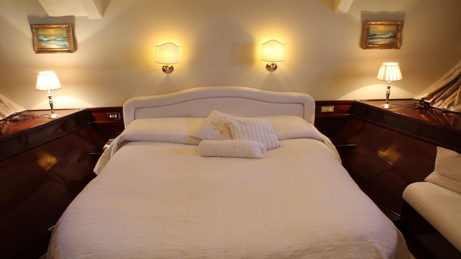 a bed with lamps on either side aboard DP MONITOR Yacht for Sale
