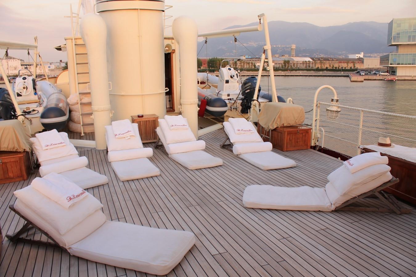 a deck with a view of a marina with boats and a city in the background aboard DP MONITOR Yacht for Sale