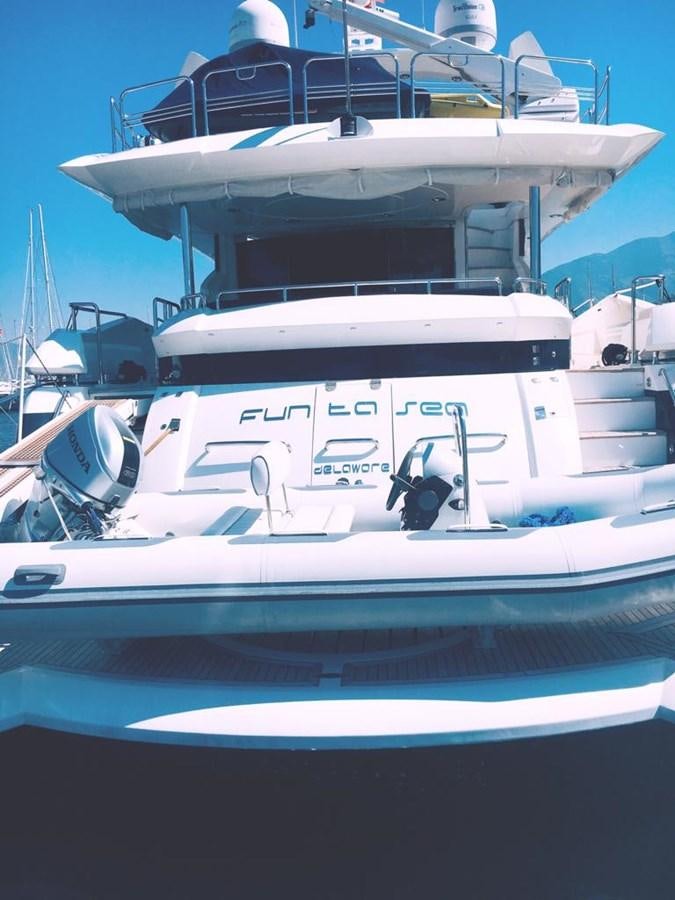 a white boat with blue and black stripes aboard FUNTASEA Yacht for Sale