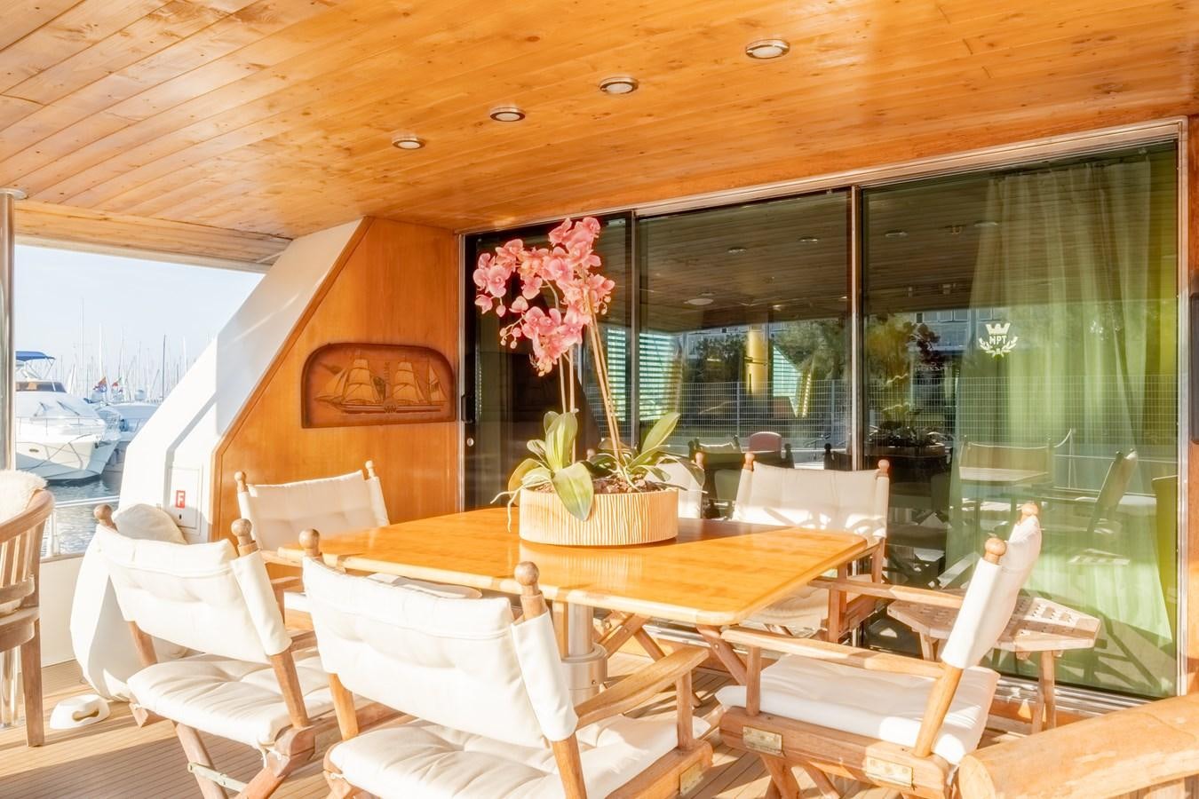 a table with chairs and a plant in a room with a window aboard TIENNA Yacht for Sale