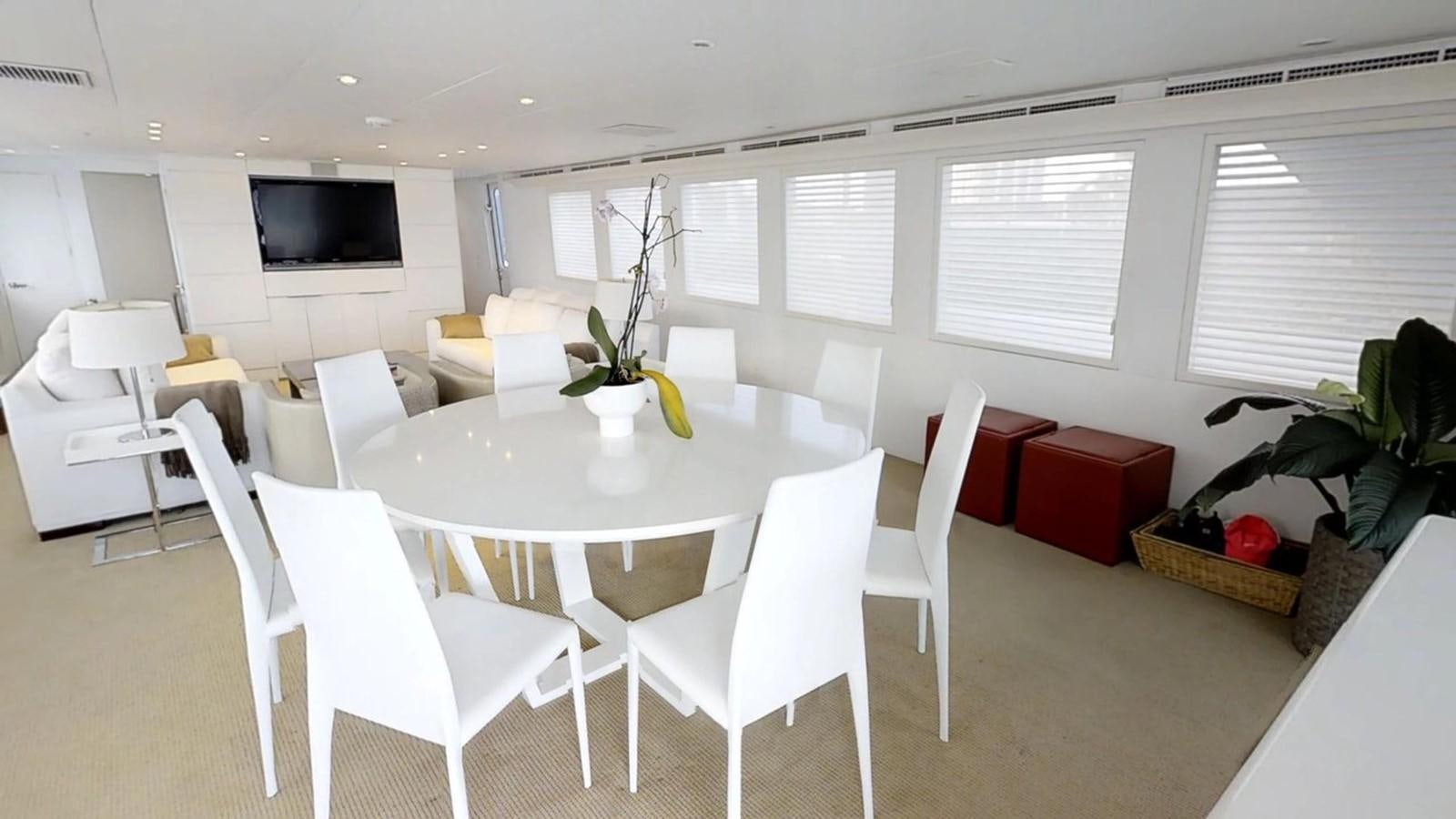 a room with white chairs and a table with a plant on it aboard 92' HATTERAS Yacht for Sale