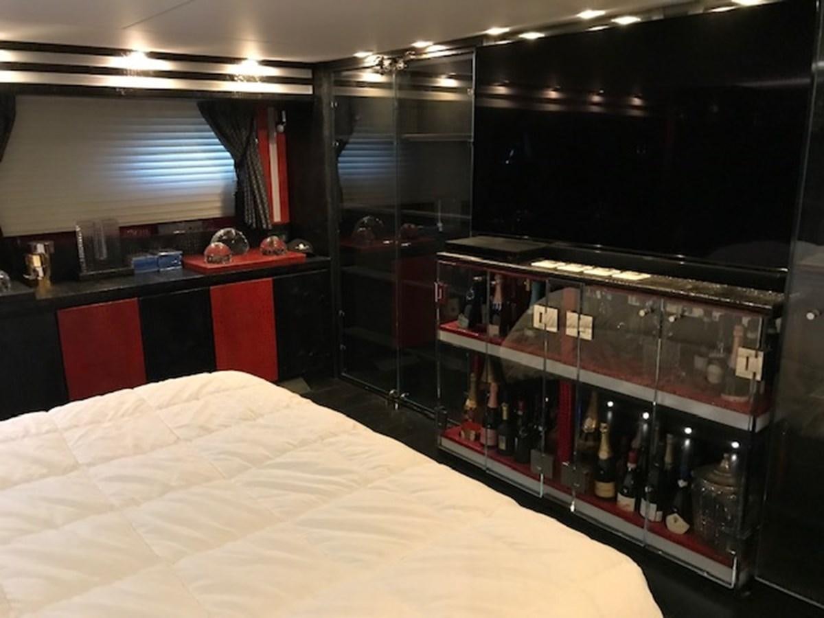 a room with a bed and bottles aboard KISSES Yacht for Sale